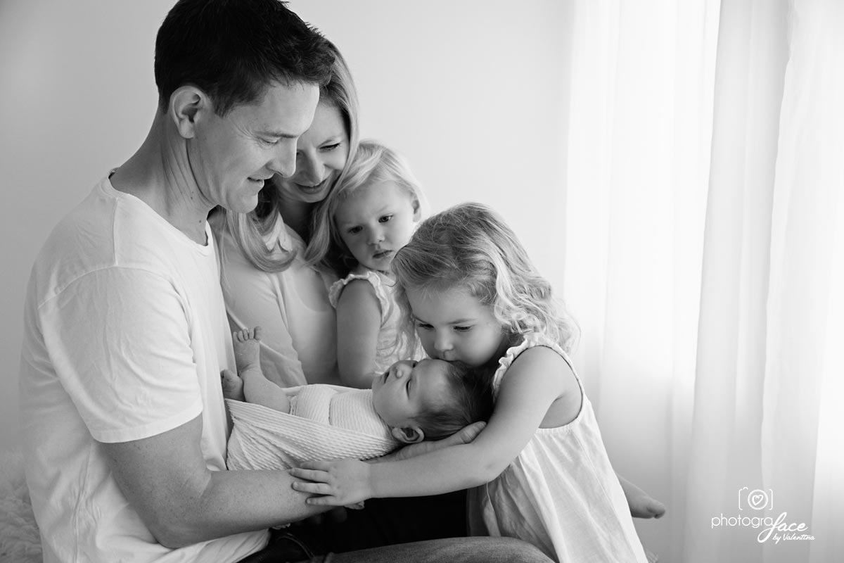dad holding newborn baby surrounded by mum and 2 girls