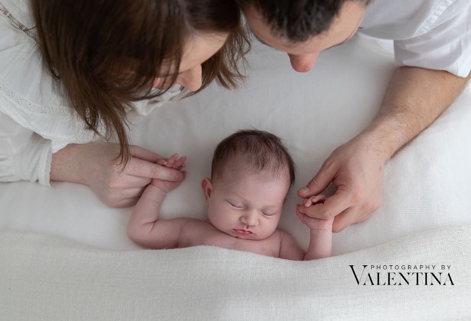 mum and dad holding baby's hands during a newborn photoshoot