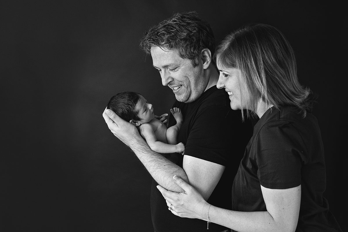 Family portrait of 3 parents and newborn