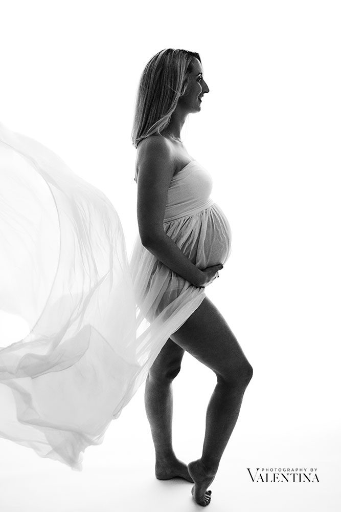 Flowing fabric for maternity photos - artistic silhouette of pregnant woman in studio