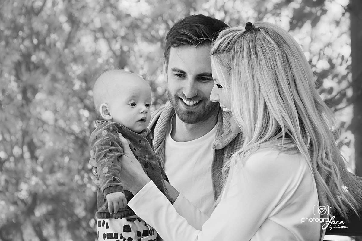mum holding baby and dad looking at then - value of photos