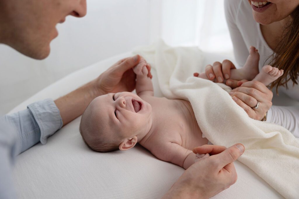 newborn baby laying on a beanbag and smiling at dad