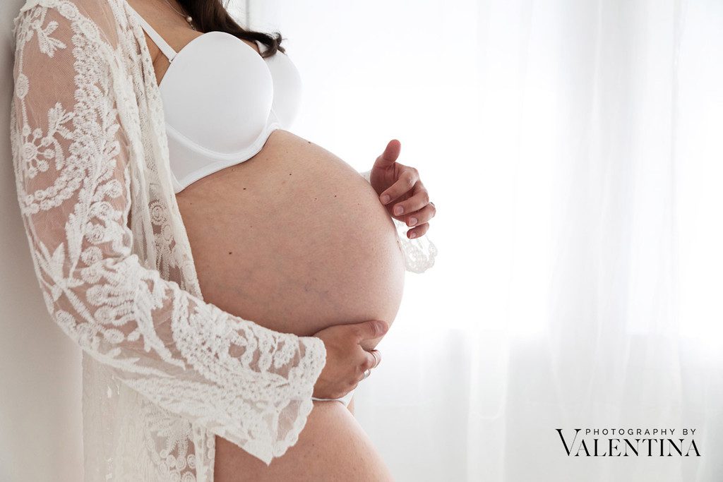 Close up image of pregnant belly in a light and airy studio