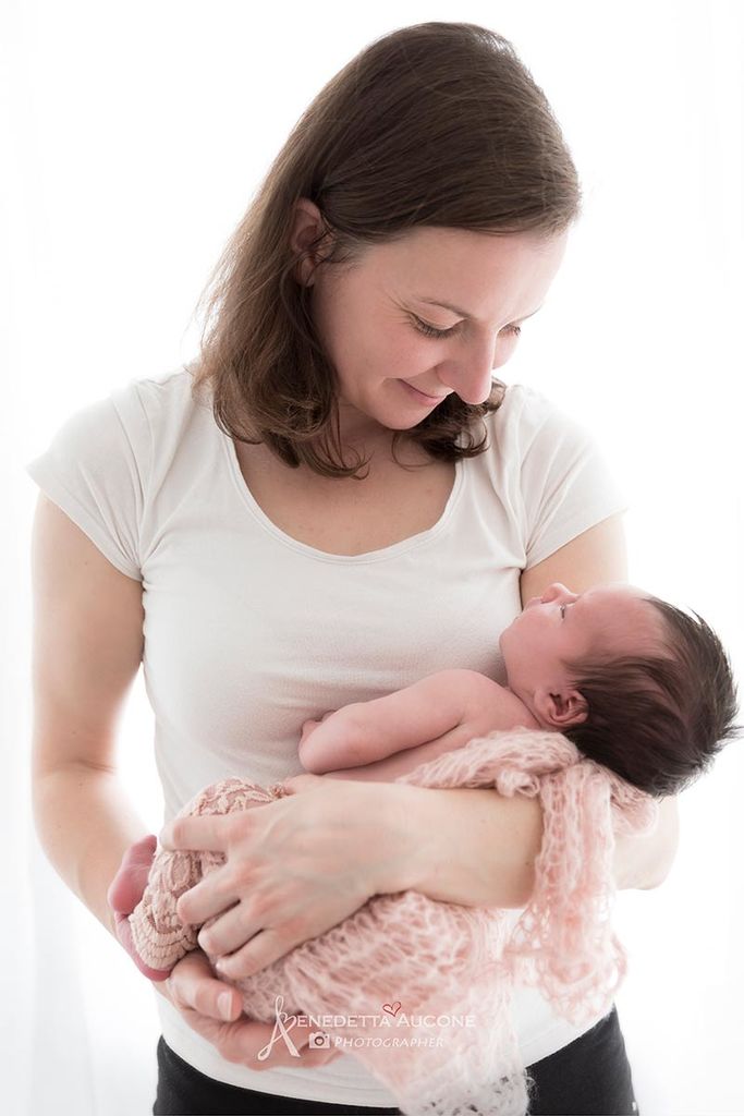 Newborn photographer Valentina holding a baby during a newborn shoot. Safe newborn posing practice