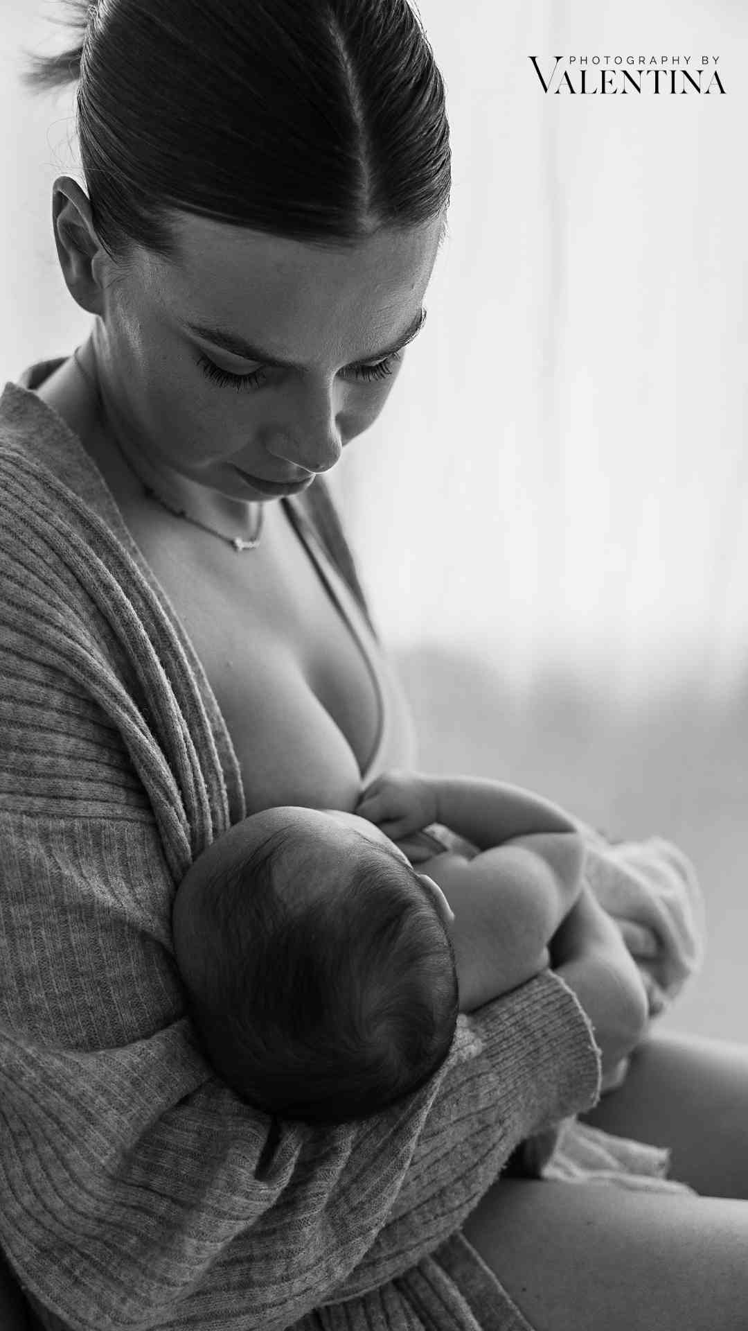 Young mother breastfeeding her baby in a quiet, intimate moment, looking down lovingly.