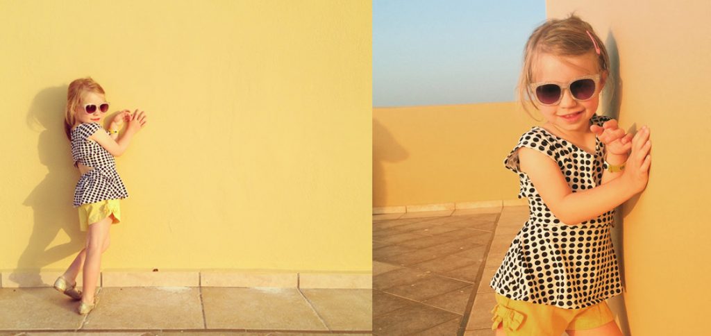little girl standing in front of a yellow wall on holiday