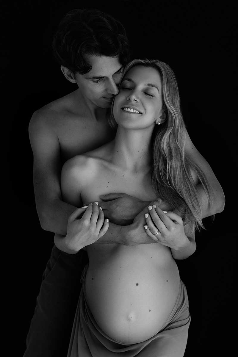 Intimate black and white maternity portrait of a couple embracing, both with bare upper bodies. London maternity photography. Photography by Valentina