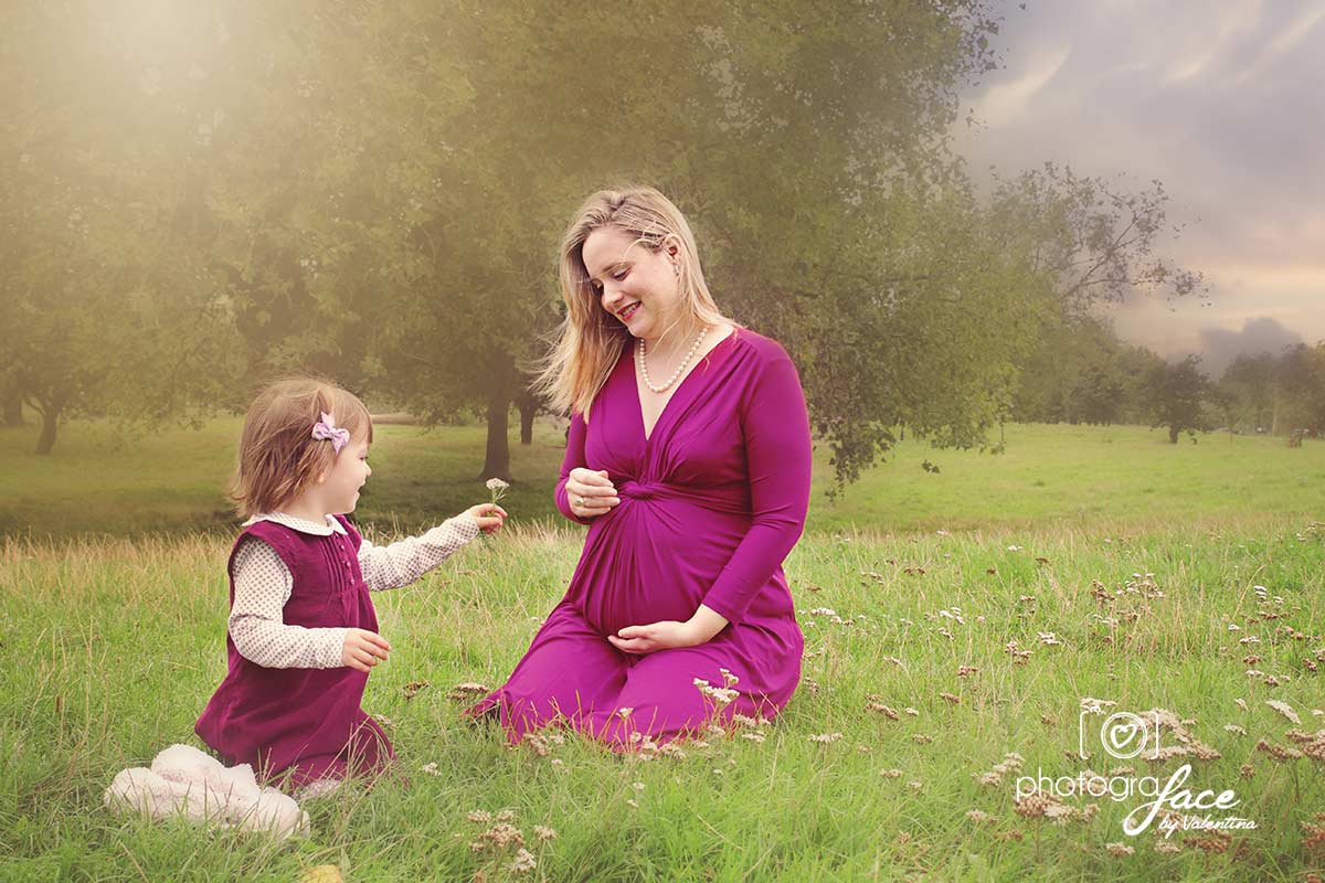 mum and daughter sitting in a park: girl is giving mum a flower