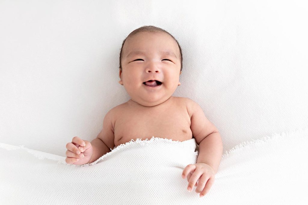 one month old baby looking up and smiling