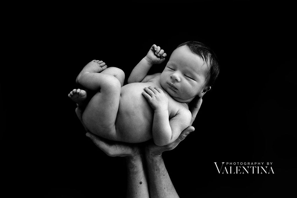 Baby in dad's hands. Black background