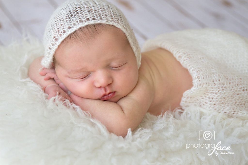 newborn baby sleeping on his tummy with hands under chin