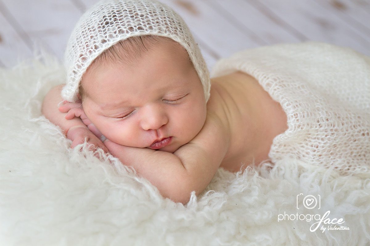 newborn baby sleeping on his tummy with hands under chin