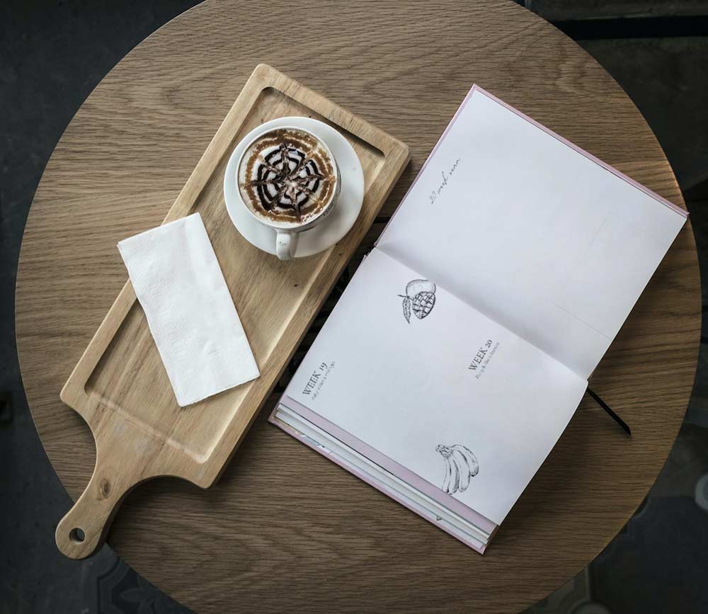 table with a pregnancy journal and a cup of coffee