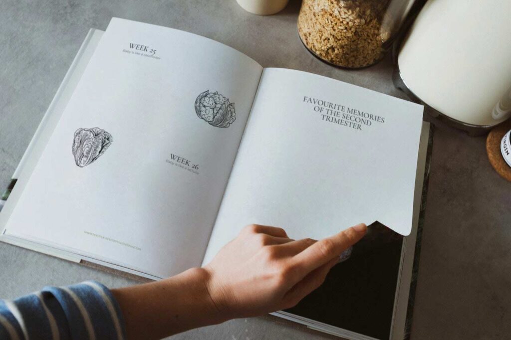 Hand of mum flipping the page of her pregnancy journal