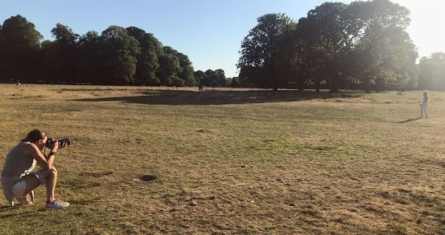 behind the scene during a child outdoor session. Photographer distant as a covid safety measure