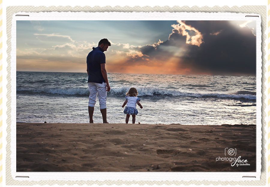 dad and daughter looking at the sea standing on the beach
