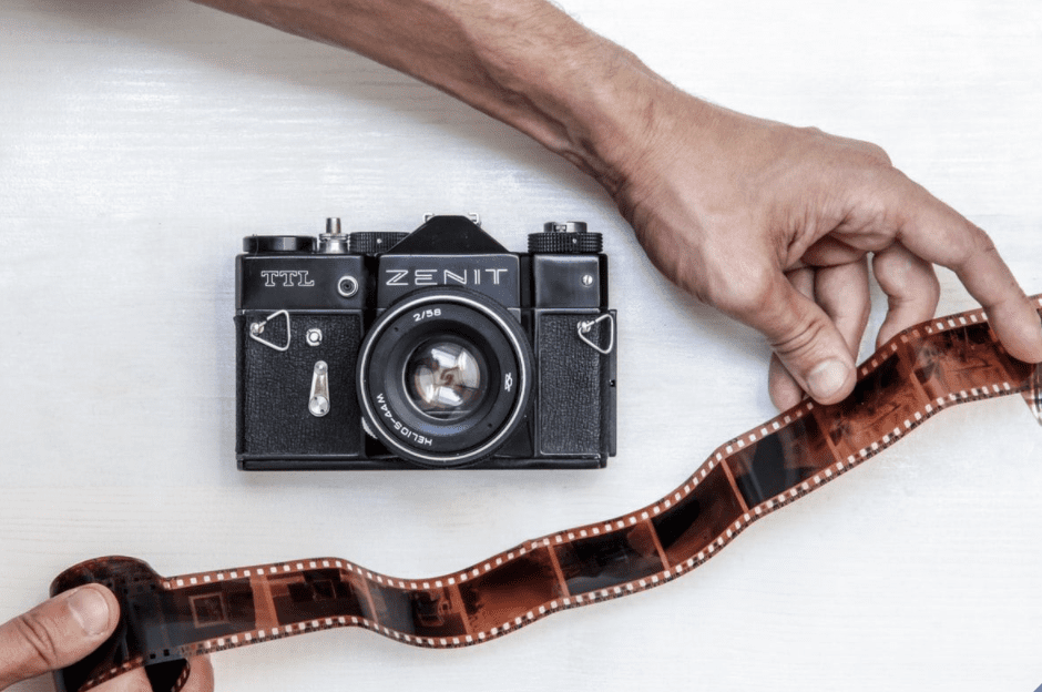Vintage Zenit film camera held by hand with exposed film roll